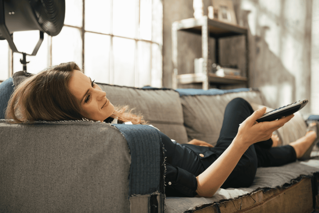Relaxed woman lying on sofa watching TV